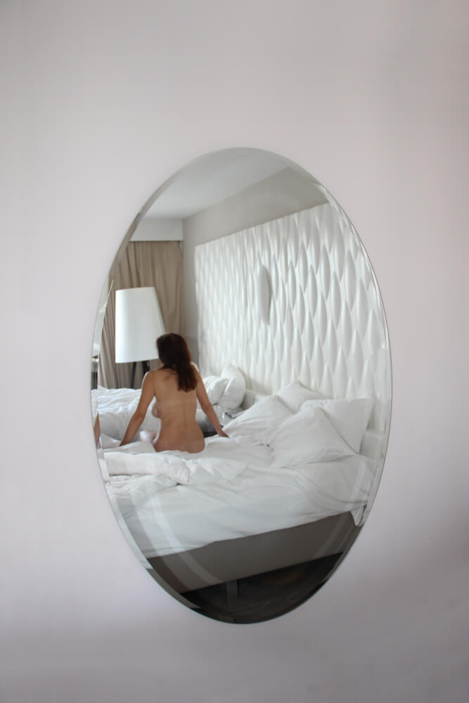 reflet d'Amélie, nue de dos, dans un miroir ovale